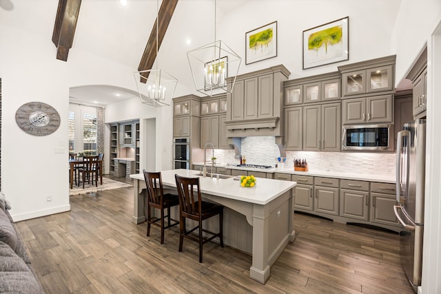 kitchen with high vaulted ceiling, gray cabinetry, a sink, stainless steel appliances, and light countertops