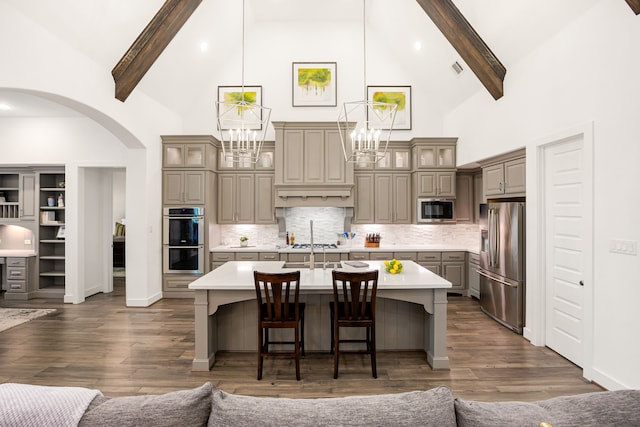 kitchen featuring a breakfast bar, a center island with sink, tasteful backsplash, stainless steel appliances, and light countertops