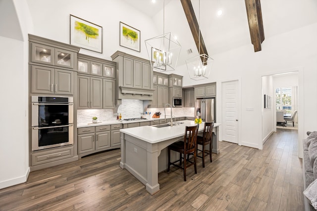 kitchen with dark wood-style floors, high vaulted ceiling, gray cabinets, appliances with stainless steel finishes, and backsplash