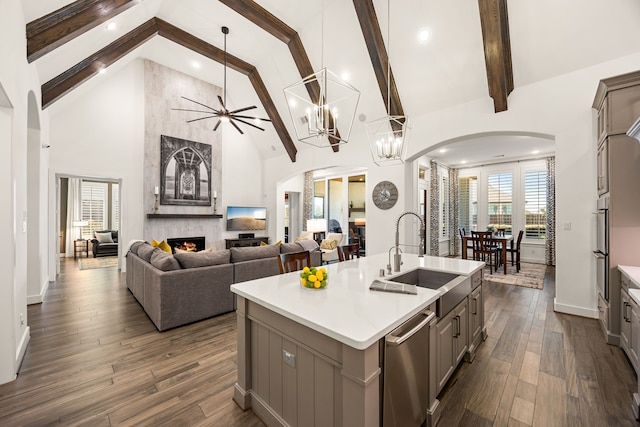 kitchen with arched walkways, gray cabinetry, a sink, dishwasher, and a large fireplace