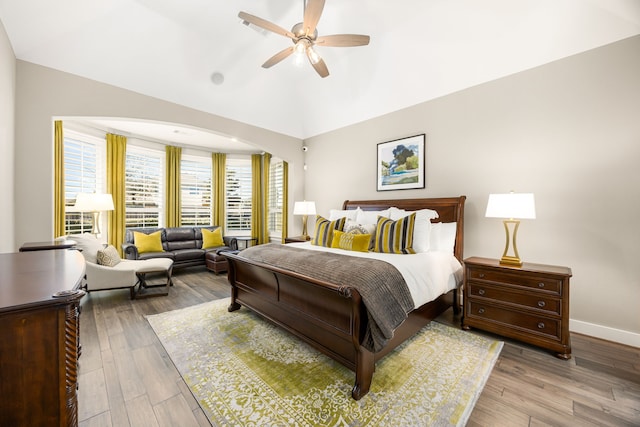 bedroom featuring lofted ceiling, wood finished floors, baseboards, and ceiling fan