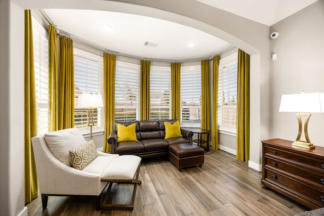 sitting room with wood finished floors, arched walkways, visible vents, and baseboards