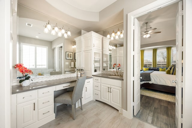 ensuite bathroom with visible vents, connected bathroom, wood finished floors, vanity, and a ceiling fan