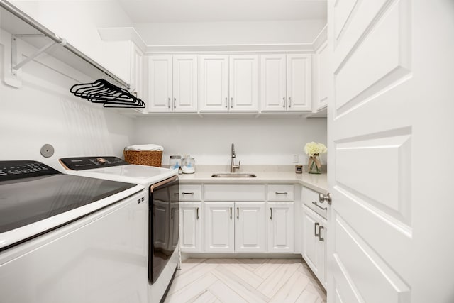 laundry area with washing machine and clothes dryer, cabinet space, and a sink