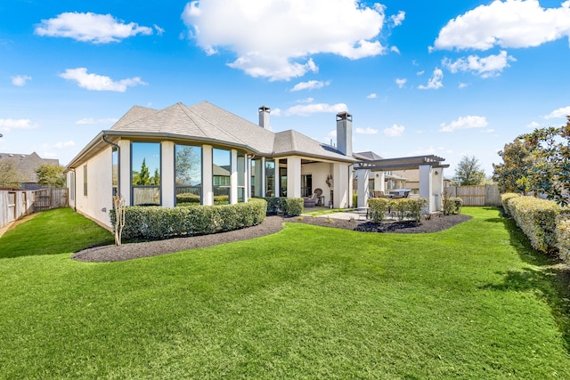 rear view of property with a shingled roof, a lawn, a chimney, a fenced backyard, and a patio area