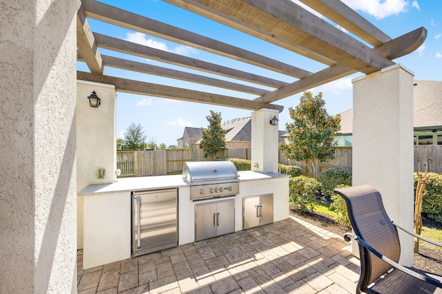 view of patio with grilling area, an outdoor kitchen, a pergola, and a fenced backyard