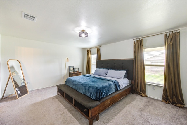 bedroom featuring visible vents, light colored carpet, and baseboards