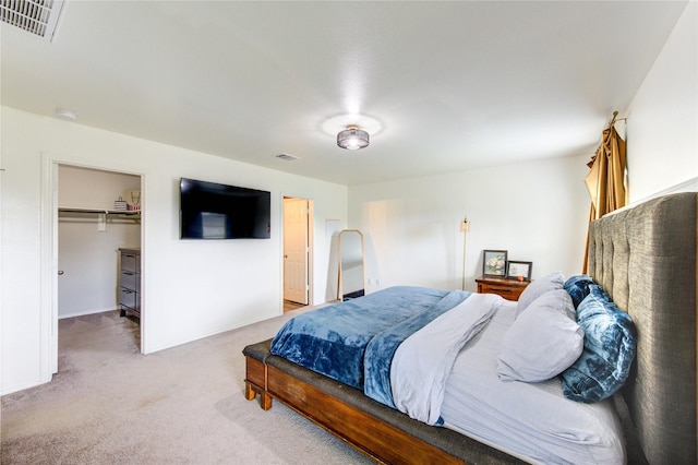 bedroom featuring a spacious closet, light colored carpet, and visible vents