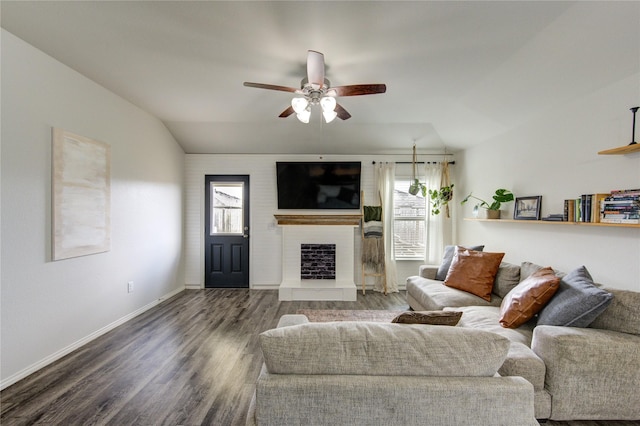 living area with a fireplace with raised hearth, baseboards, vaulted ceiling, wood finished floors, and a ceiling fan