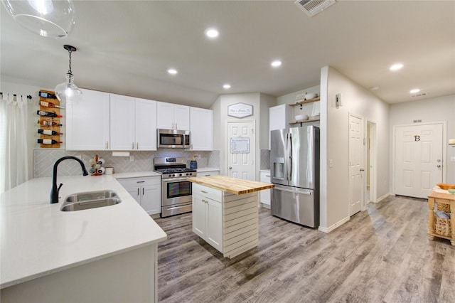 kitchen with visible vents, butcher block countertops, light wood-style flooring, stainless steel appliances, and a sink