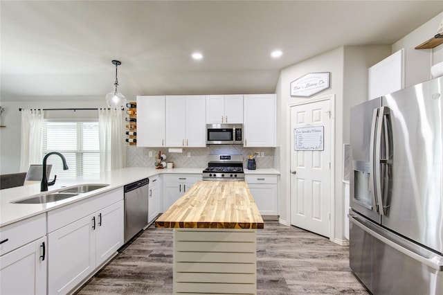 kitchen featuring butcher block countertops, white cabinets, stainless steel appliances, and a sink