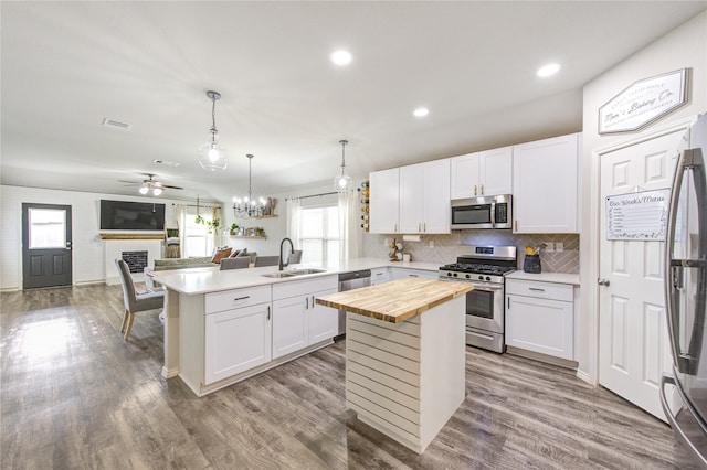 kitchen with a peninsula, a fireplace, stainless steel appliances, wood counters, and a sink