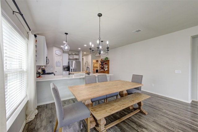 dining space with dark wood finished floors, visible vents, baseboards, and an inviting chandelier