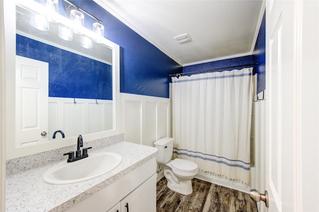 bathroom featuring vanity, wood finished floors, a wainscoted wall, toilet, and a textured wall