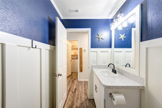 bathroom featuring visible vents, vanity, a textured wall, and wood finished floors