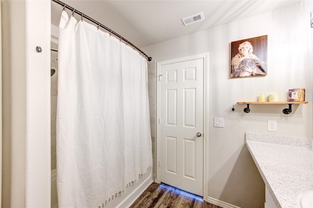 bathroom with vanity, wood finished floors, visible vents, baseboards, and shower / bath combo