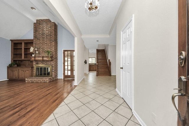 foyer with baseboards, stairs, lofted ceiling with beams, light wood-style flooring, and a fireplace