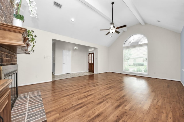 unfurnished living room with wood finished floors, a brick fireplace, beamed ceiling, and visible vents