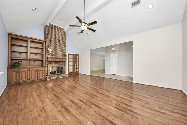 unfurnished living room with visible vents, a brick fireplace, beamed ceiling, light wood-style flooring, and a ceiling fan