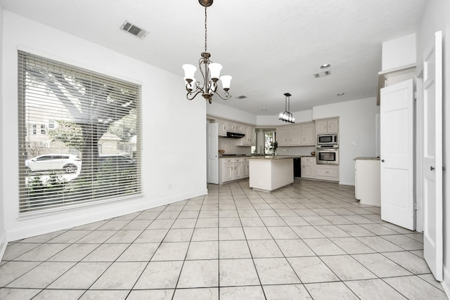 kitchen with an inviting chandelier, visible vents, appliances with stainless steel finishes, and a kitchen island