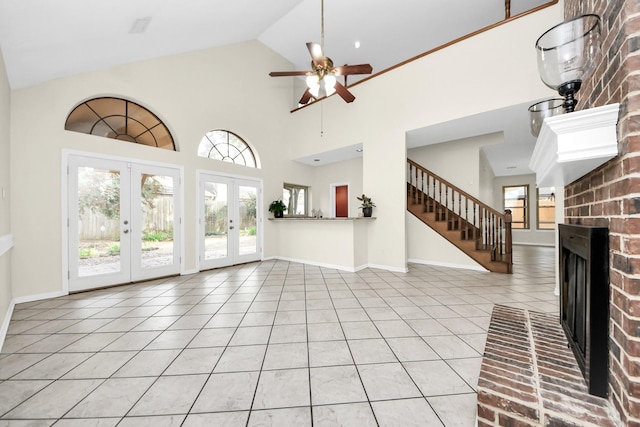 unfurnished living room featuring a ceiling fan, baseboards, light tile patterned flooring, a fireplace, and french doors