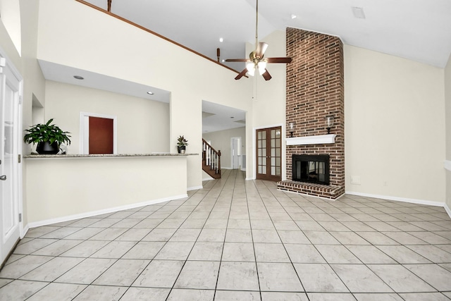 unfurnished living room featuring stairway, baseboards, high vaulted ceiling, a fireplace, and ceiling fan