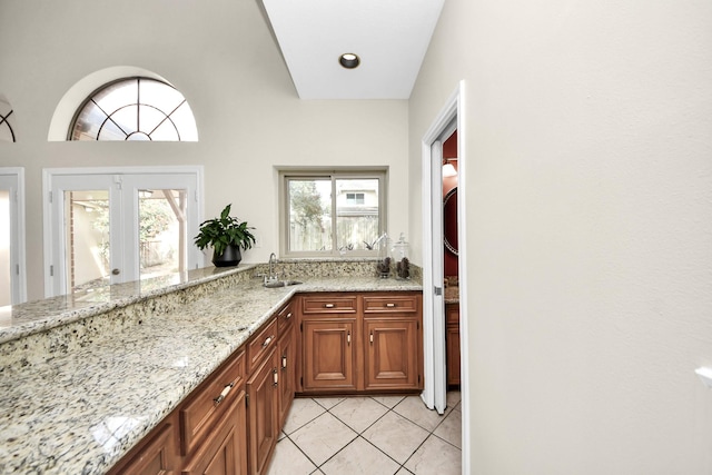 kitchen with light tile patterned floors, light stone countertops, a wealth of natural light, and a sink