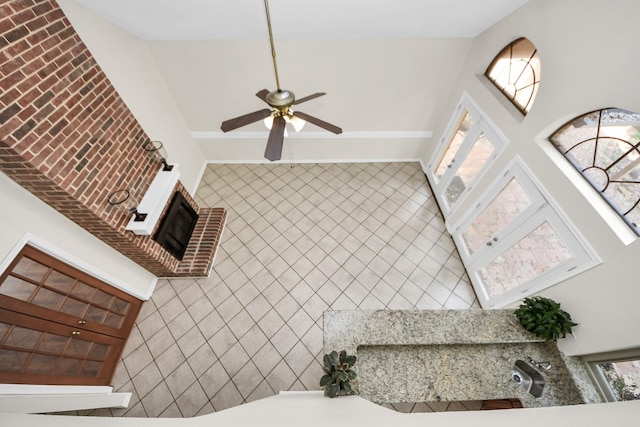 interior space with a brick fireplace and a ceiling fan