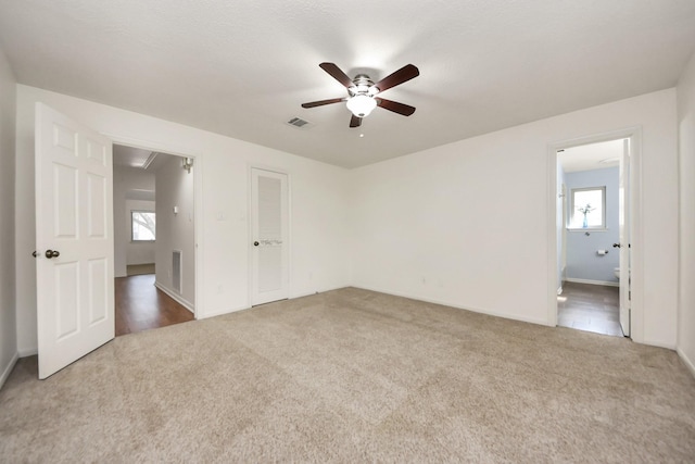 empty room featuring attic access, a ceiling fan, visible vents, and carpet floors