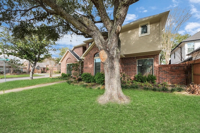 view of front of home with brick siding, a front lawn, and fence