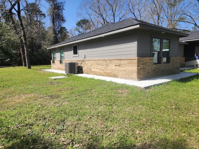 view of side of home with brick siding, central air condition unit, and a lawn