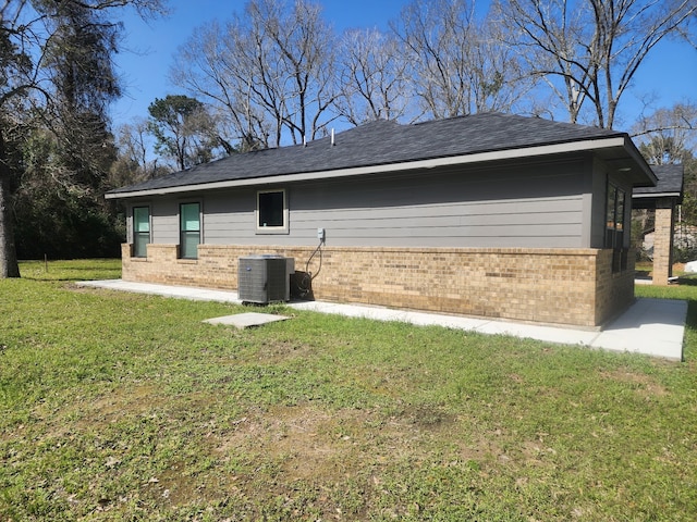 back of property featuring a yard, brick siding, and central AC