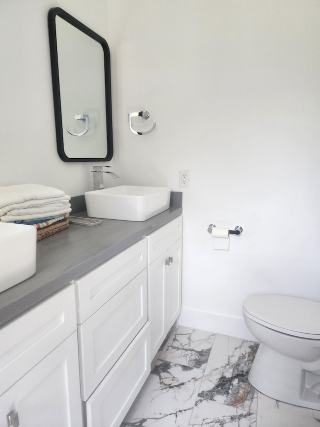 bathroom with baseboards, toilet, marble finish floor, and vanity