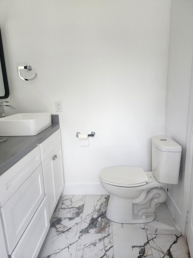 bathroom with vanity, toilet, baseboards, and marble finish floor