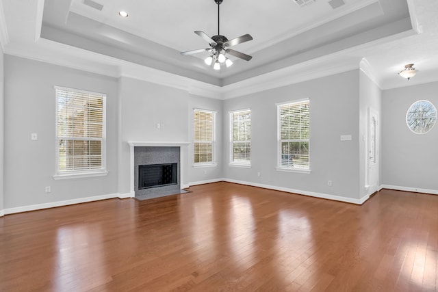 unfurnished living room with a raised ceiling, hardwood / wood-style flooring, a fireplace with flush hearth, and baseboards