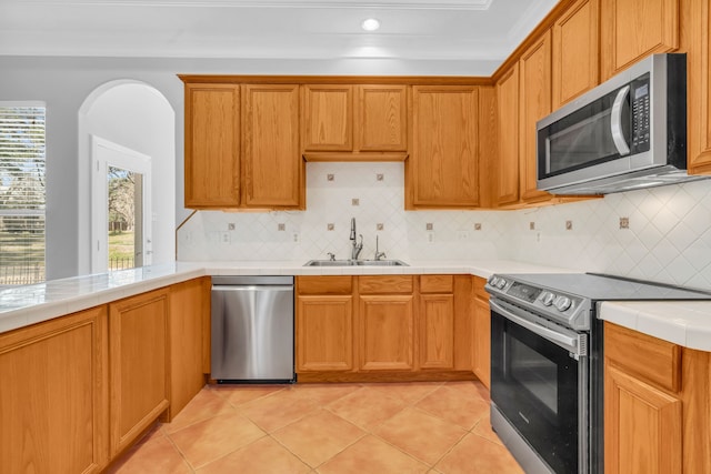 kitchen with light tile patterned floors, a sink, tile counters, appliances with stainless steel finishes, and backsplash