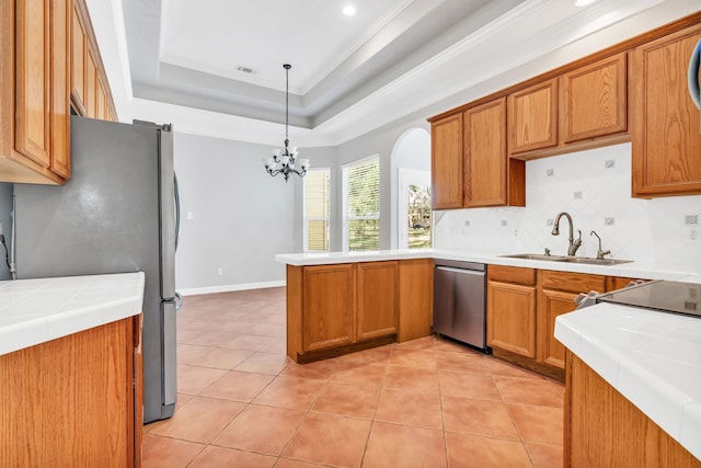 kitchen with a sink, tasteful backsplash, stainless steel appliances, a peninsula, and a raised ceiling