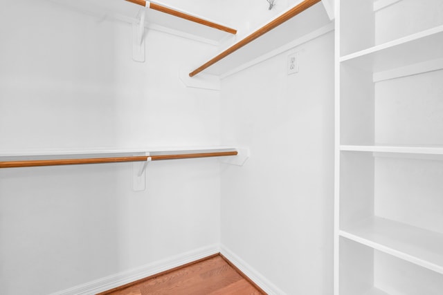 walk in closet with wood finished floors