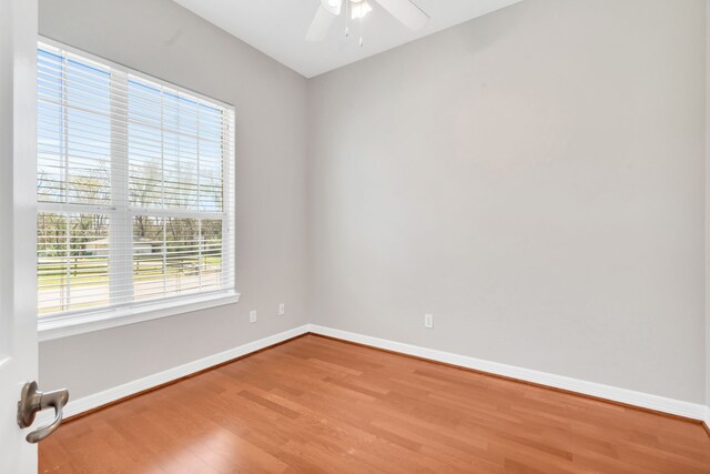 empty room featuring ceiling fan, baseboards, and wood finished floors