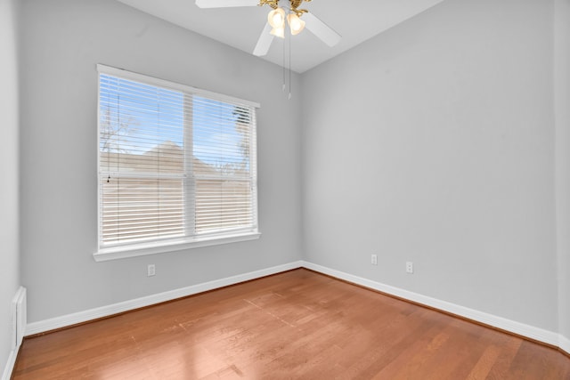 empty room with a healthy amount of sunlight, ceiling fan, baseboards, and wood finished floors