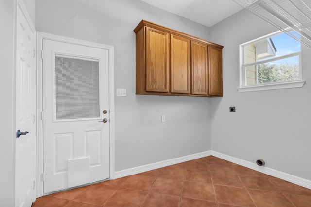 laundry area with baseboards, hookup for an electric dryer, cabinet space, and tile patterned flooring