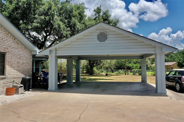 view of vehicle parking with a carport, driveway, and fence