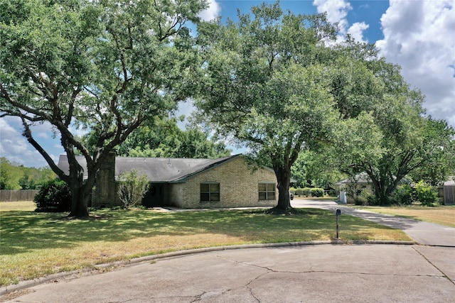 view of front facade with driveway, brick siding, and a front lawn