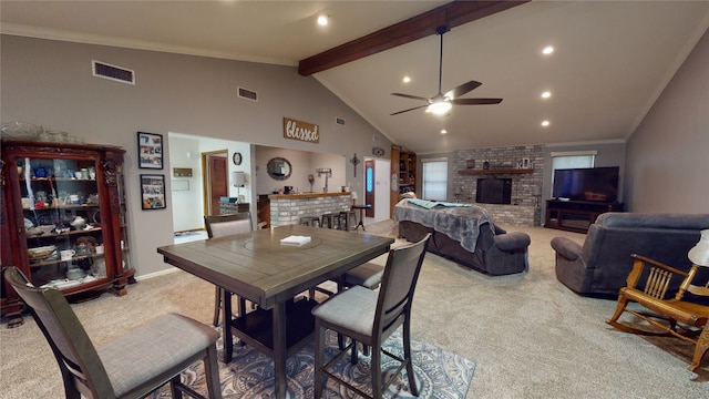 dining space featuring beamed ceiling, carpet floors, a brick fireplace, and visible vents