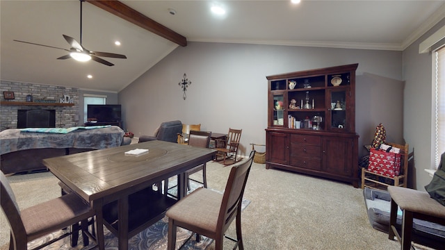 dining room featuring a brick fireplace, ceiling fan, light colored carpet, lofted ceiling with beams, and ornamental molding