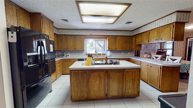 kitchen featuring wallpapered walls, brown cabinetry, black fridge with ice dispenser, and a peninsula