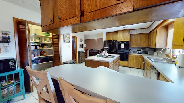 kitchen with light tile patterned floors, a kitchen island, a sink, black appliances, and light countertops