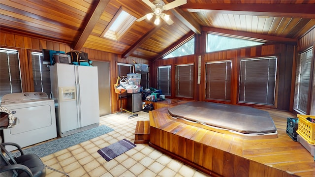 bedroom featuring wooden walls, light floors, vaulted ceiling with skylight, washer / clothes dryer, and white fridge with ice dispenser