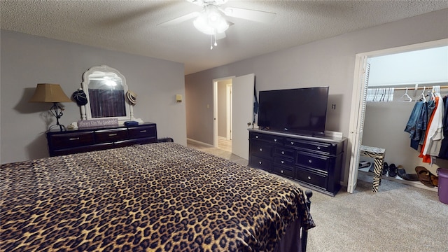 bedroom featuring a closet, light colored carpet, ceiling fan, and a textured ceiling