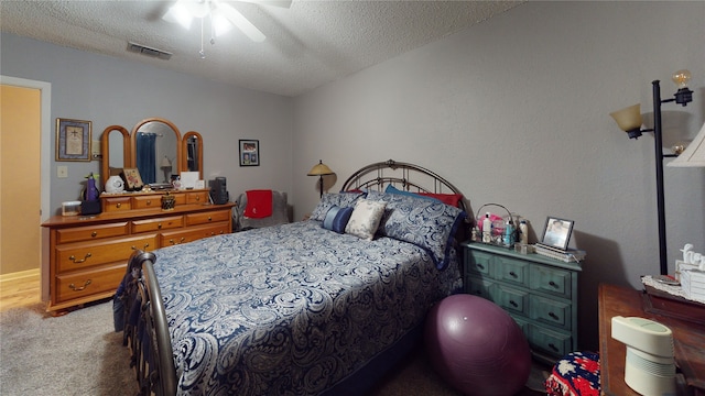 carpeted bedroom with visible vents, a textured ceiling, and ceiling fan